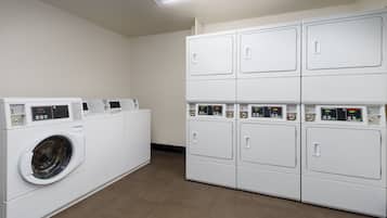 A laundry room with a front-loading washing machine and stacked dryers.