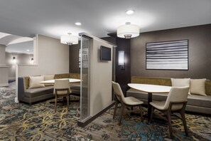 A hotel room with a sofa, a dining table, and chairs. There is a television on the wall and a window with curtains. - Residence Inn By Marriott Hartford Rocky Hill (Rocky Hill)