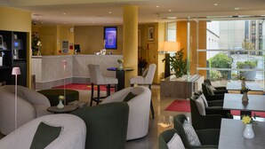 A hotel lobby with sofas, a reception desk, and a view of the street. - Hotel Parc Plaza (Luxembourg City)