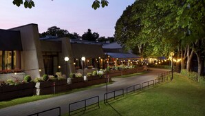 A modern building with a paved walkway, outdoor seating area, and string lights. - Hotel Parc Plaza (Luxembourg City)