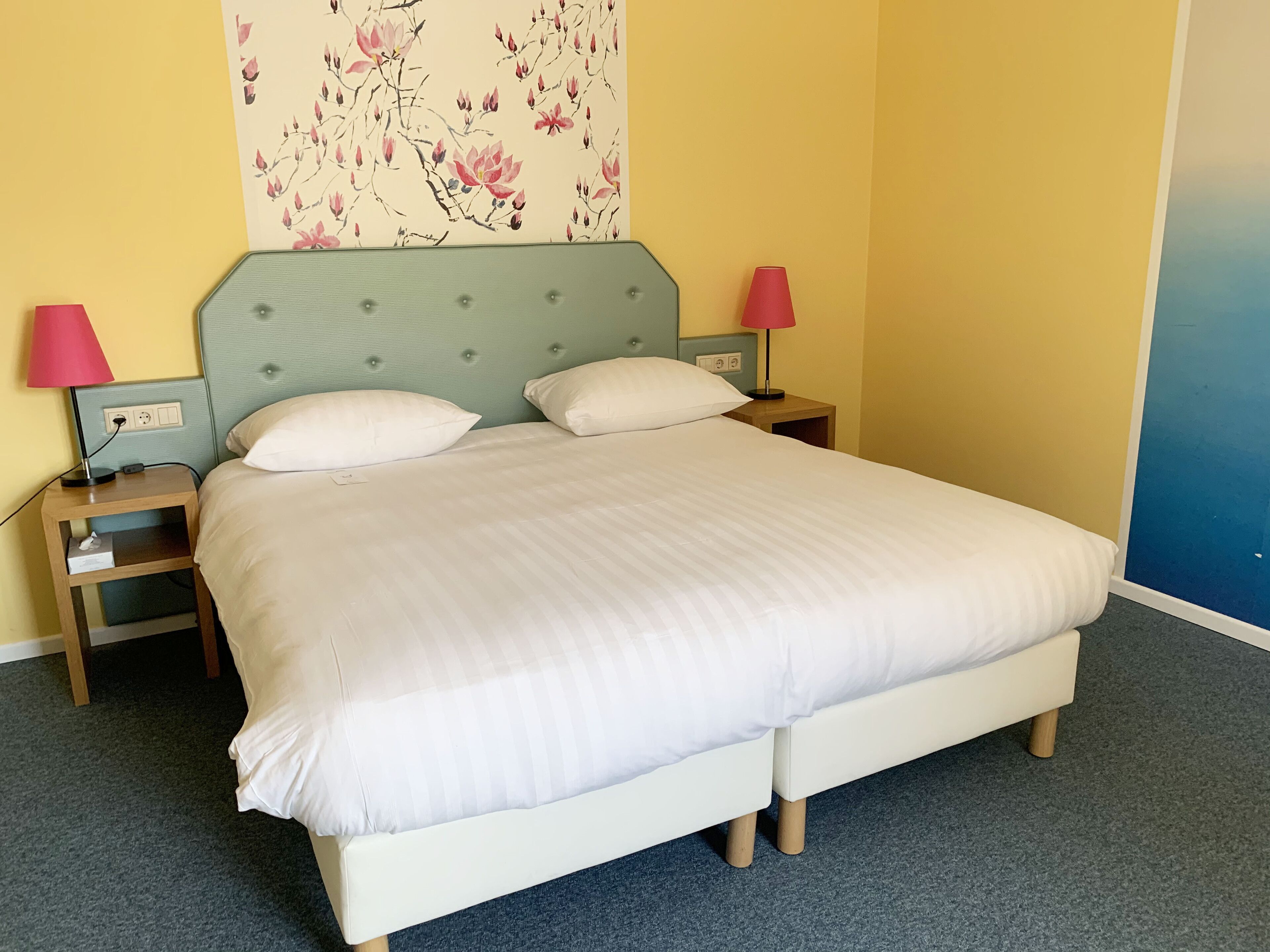 A bed with a headboard, two bedside tables, and lamps.