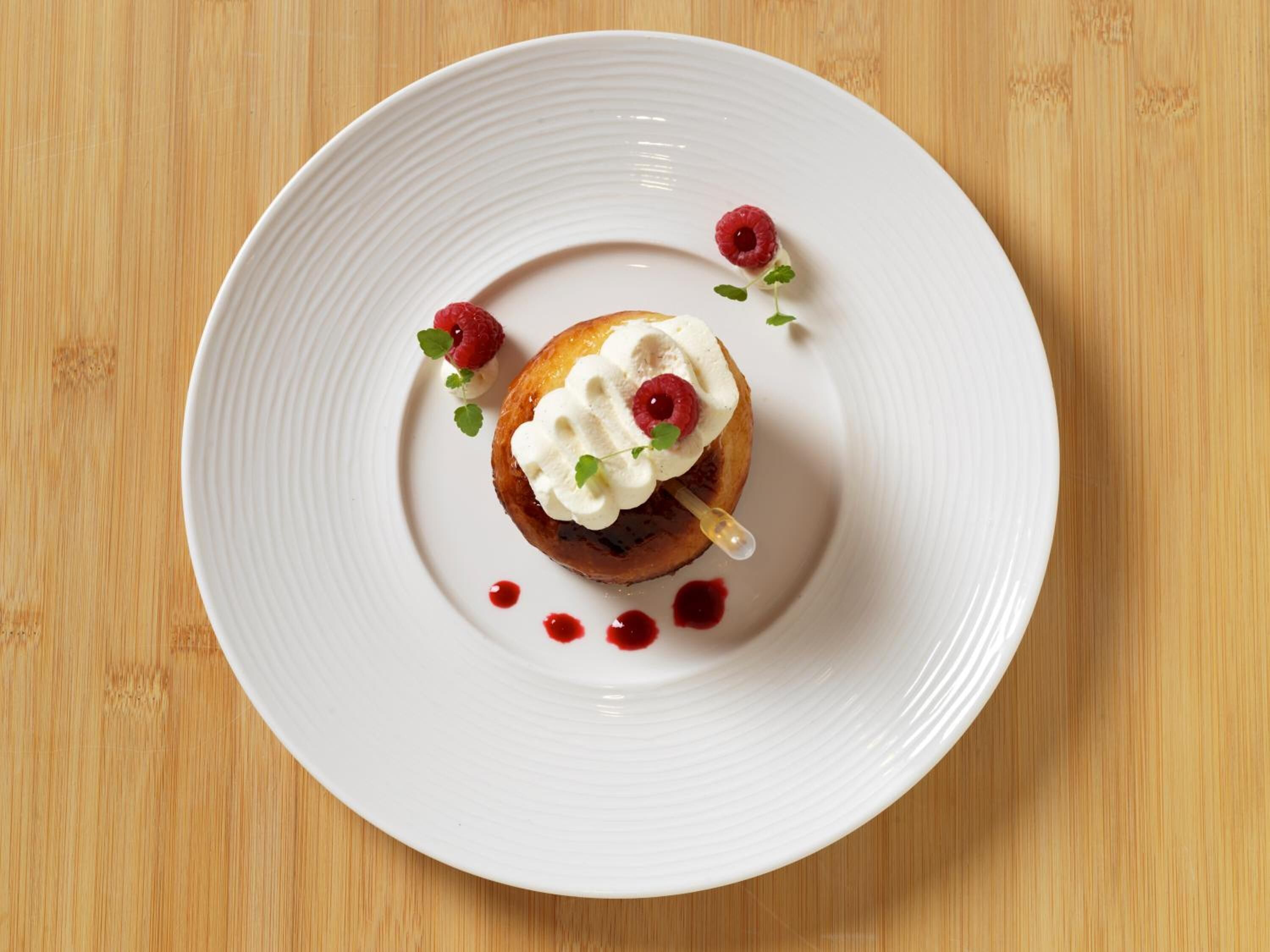 Une assiette blanche avec un dessert posé sur une table en bois.