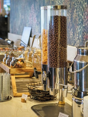 Una estación de café con varios dispensadores y recipientes de granos de café y leche condensada.