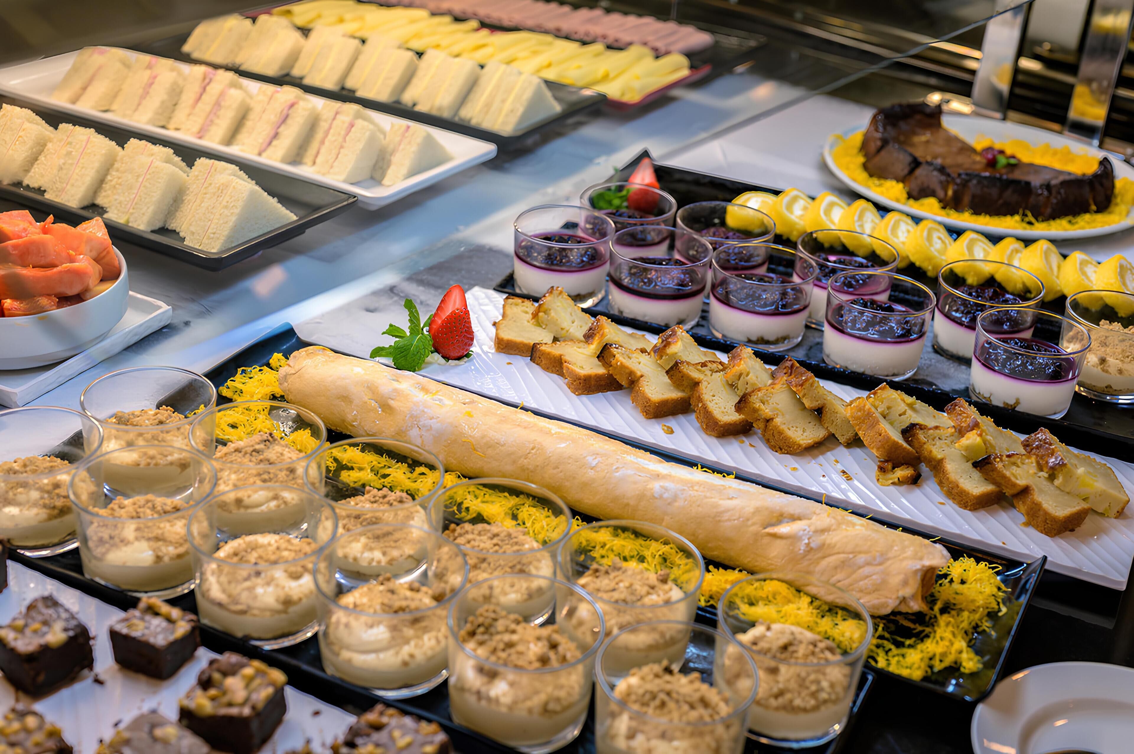 Buffet amb diferents plats, incloent entrepans, postres i pa.