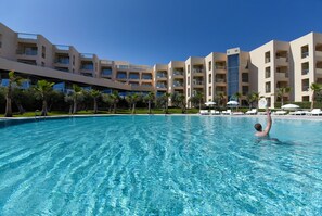 Una piscina techada, una piscina al aire libre, sombrillas