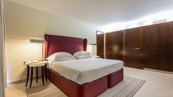A hotel room with a large bed, a bedside table, a lamp, a wardrobe, and a striped rug.