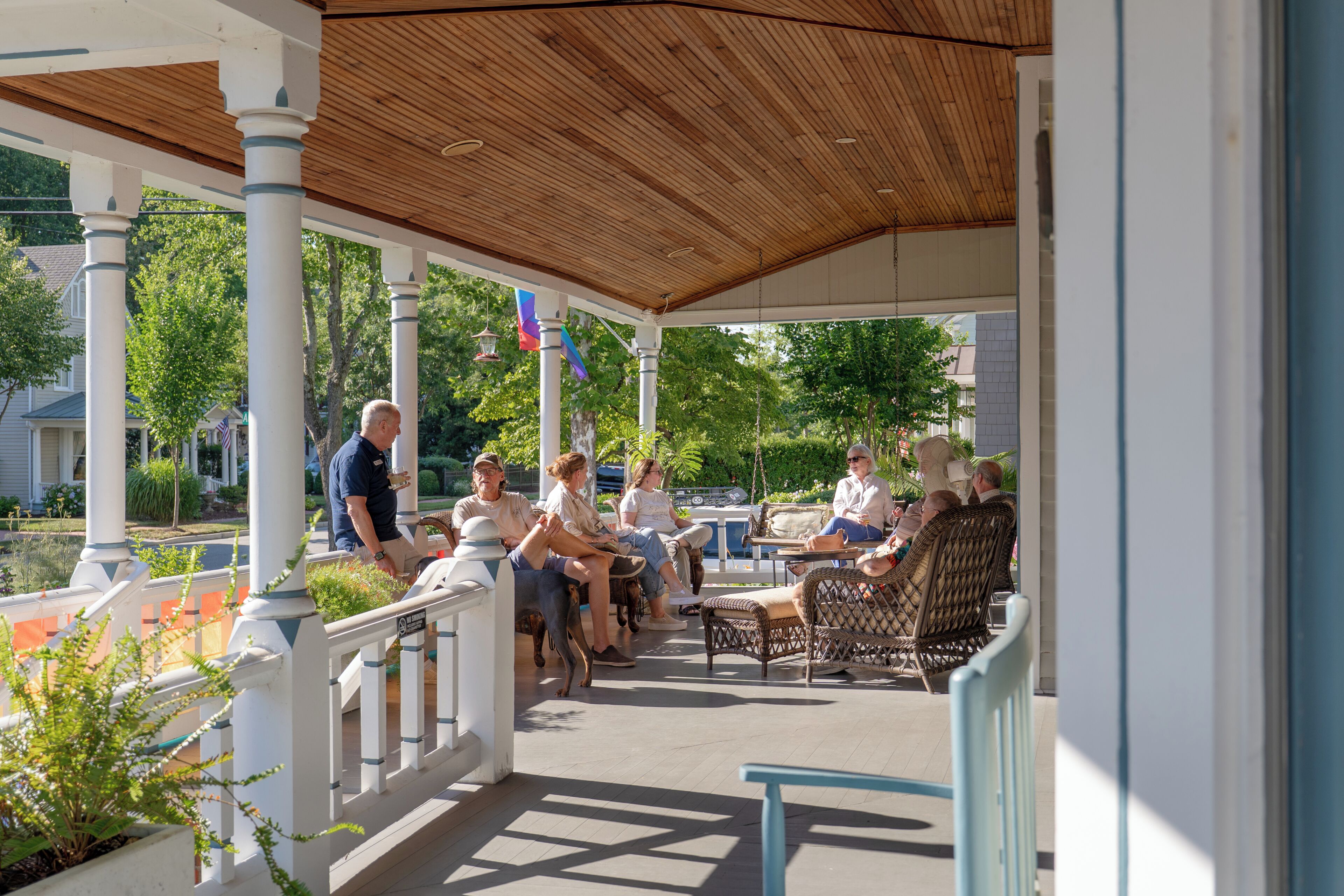 A covered outdoor seating area with white columns and a wooden ceiling.