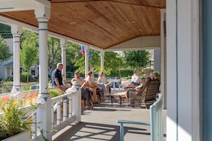 A covered outdoor seating area with white columns and a wooden ceiling. - Hummingbird Inn (Easton)