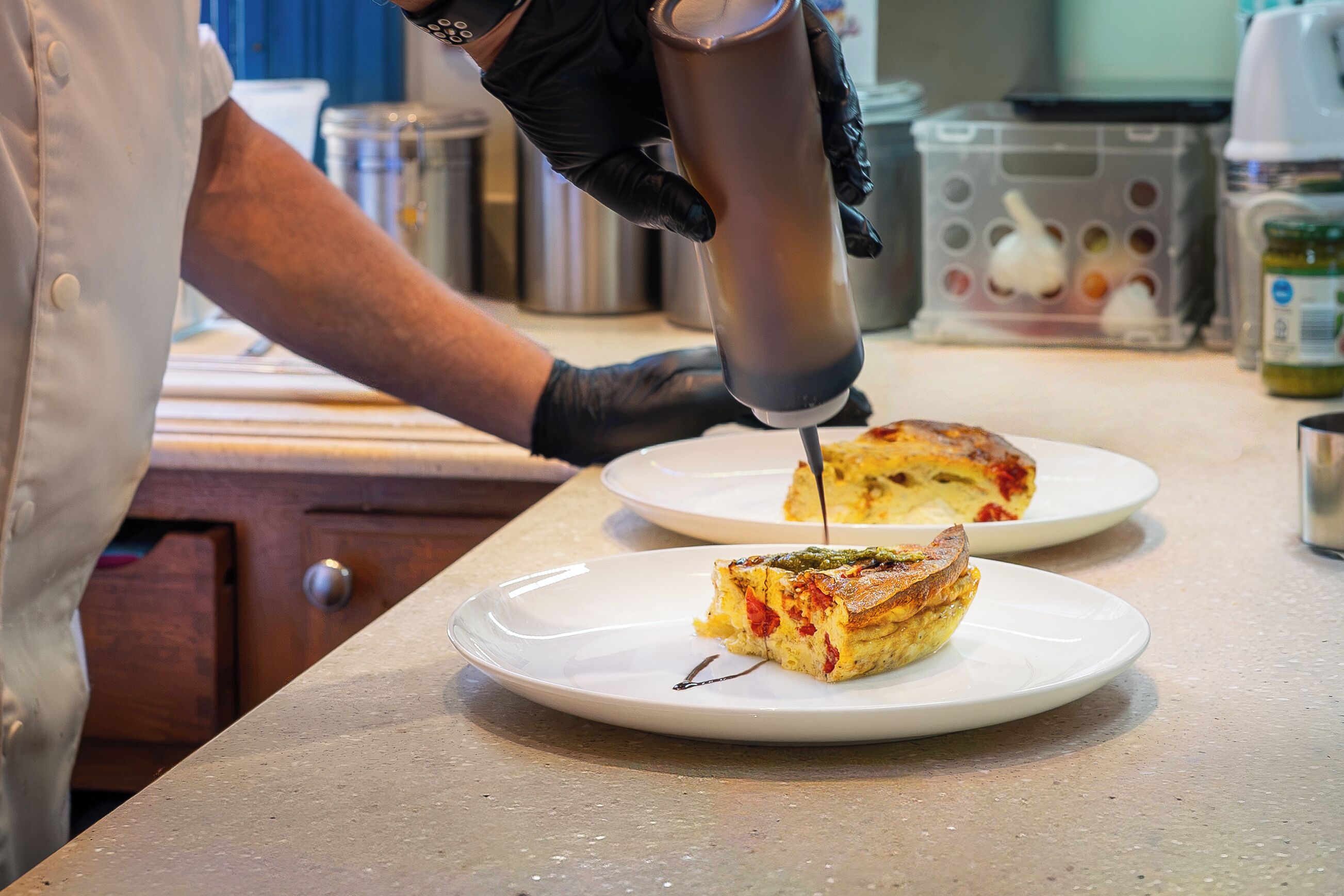 A chef pouring sauce onto a dish.