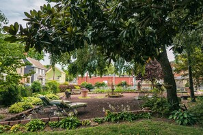 A garden with a fountain, seating area, and a variety of plants. - Hummingbird Inn (Easton)