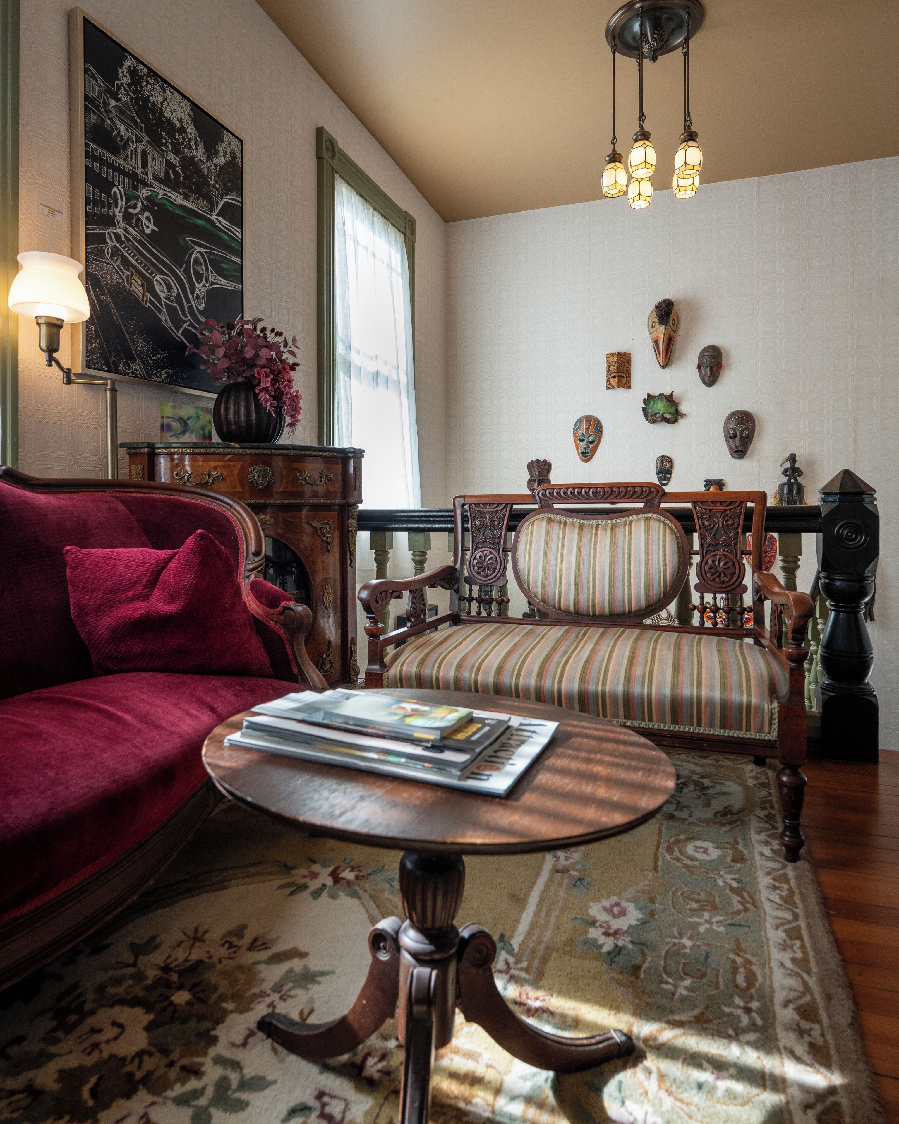 Een gezellige woonkamer met een rode bank, een gestreept fauteuil, een houten salontafel en een kamerkleed met dessin.
