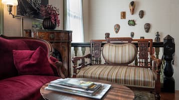 Een gezellige woonkamer met een rode bank, een gestreept fauteuil, een houten salontafel en een kamerkleed met dessin.