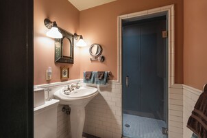 Un baño con un lavamanos blanco, un espejo y una puerta azul.