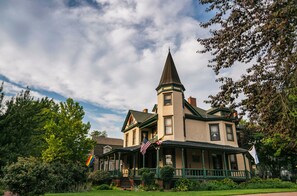 A historic house with a prominent tower, a front porch, and a flag. - Hummingbird Inn (Easton)
