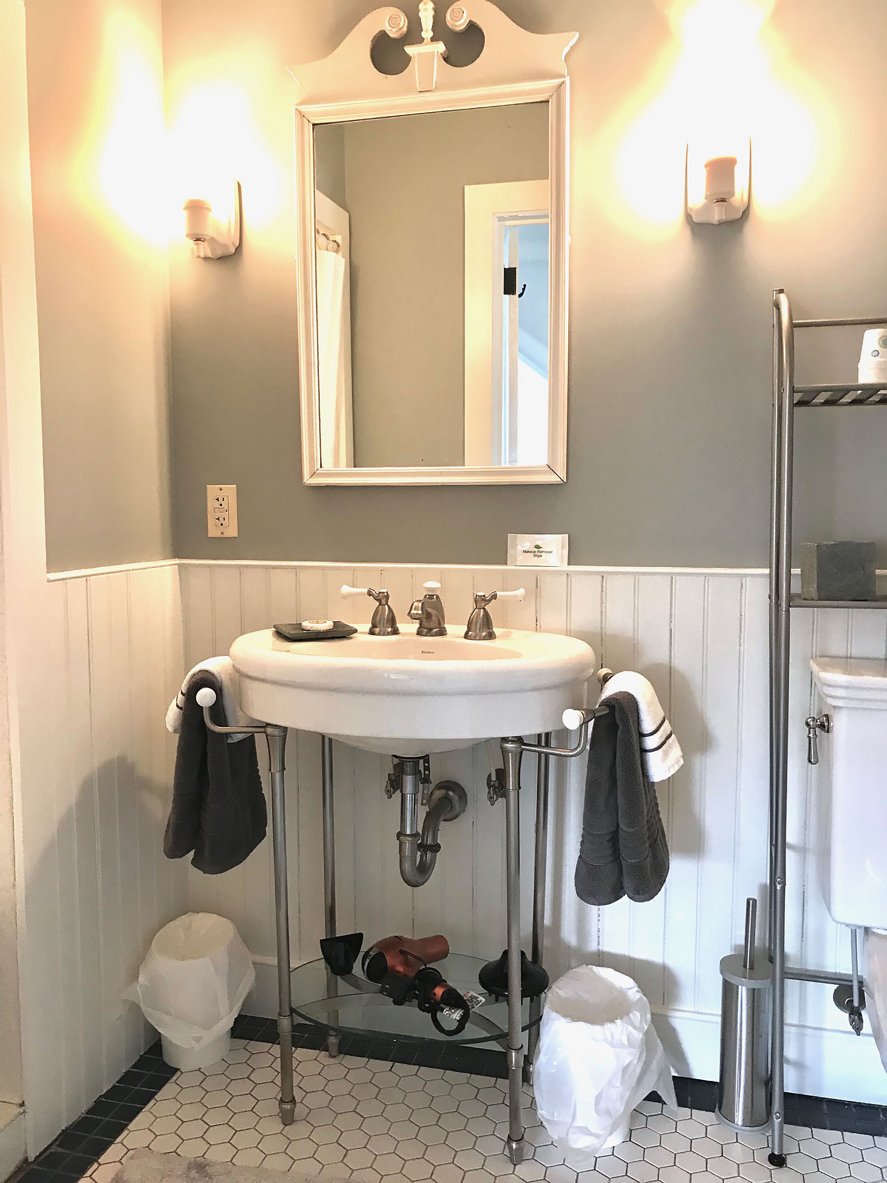 A bathroom with a white sink, two faucets, a mirror, and a towel rack.