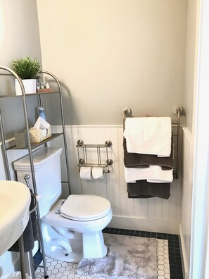 Ein Badezimmer mit Toilette, Waschbecken, Handtuchhalter und Ablage für Toilettenartikel.