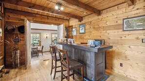Ein Holzinterieur mit Barbereich, Holzboden und einem Essbereich mit Stühlen und Tisch.