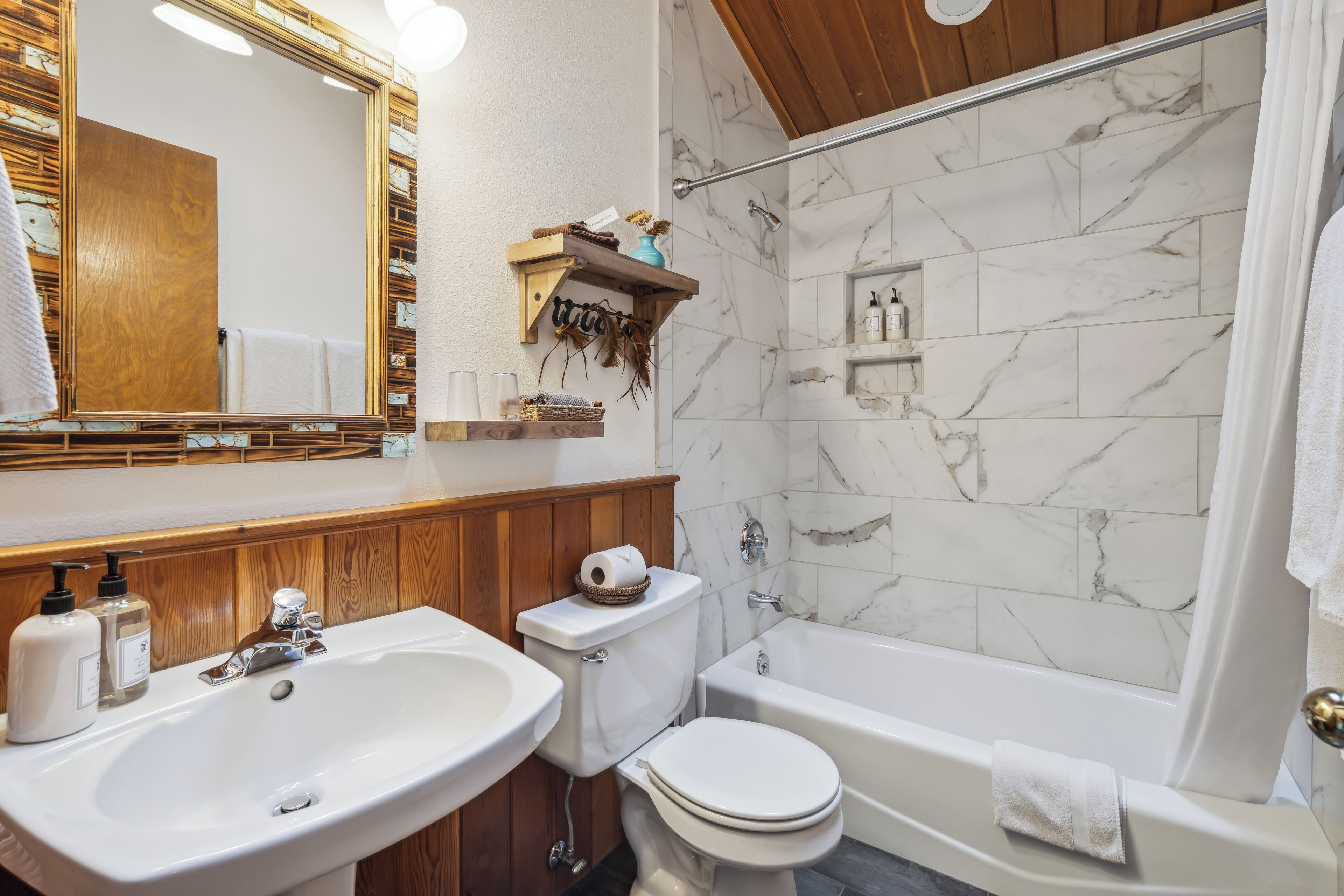 A bathroom with a wooden vanity, a sink, a toilet, and a bathtub.