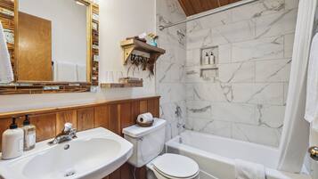 A bathroom with a wooden vanity, a sink, a toilet, and a bathtub.