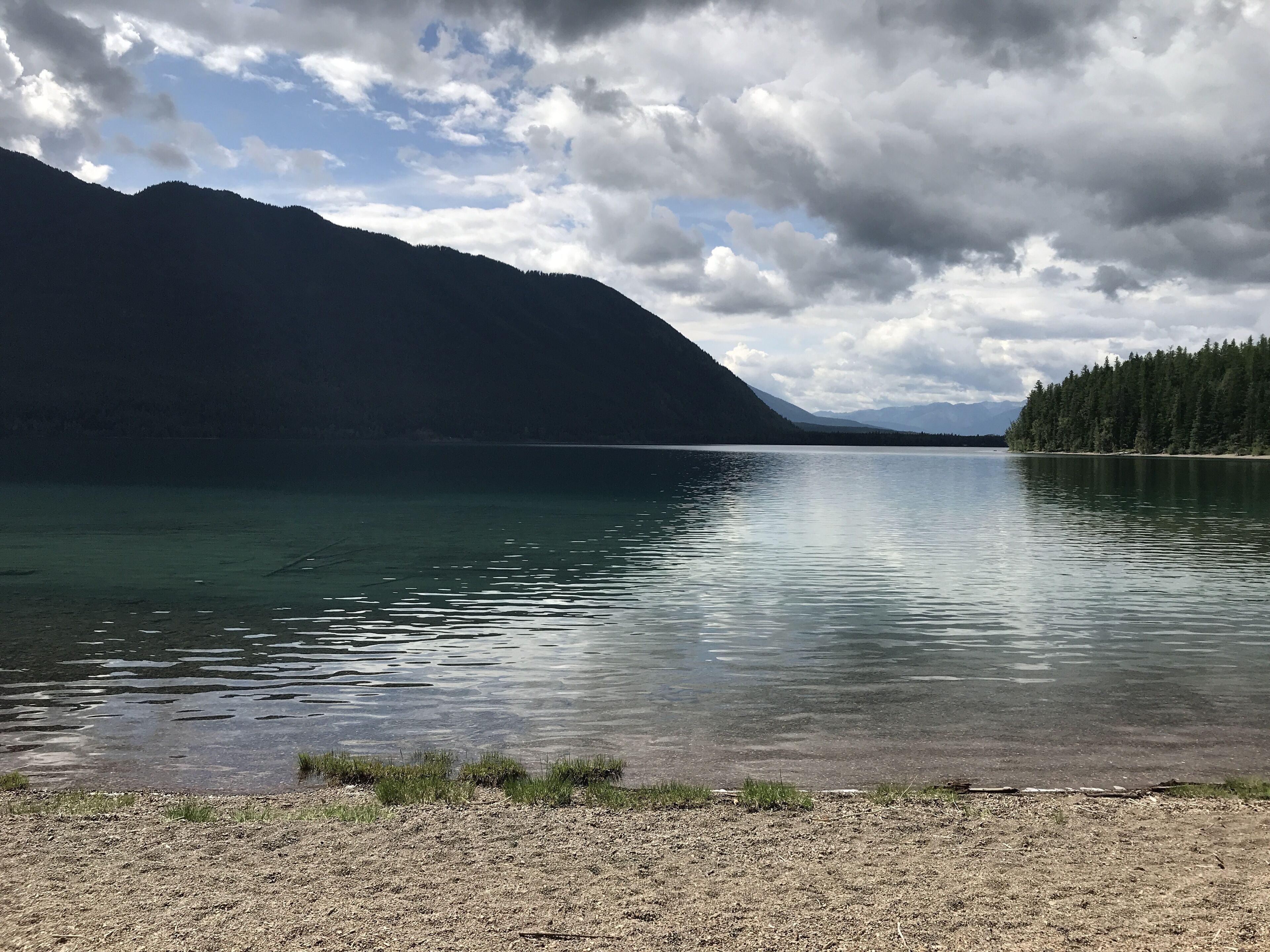 Un lac paisible, avec une montagne boisée en arrière-plan.