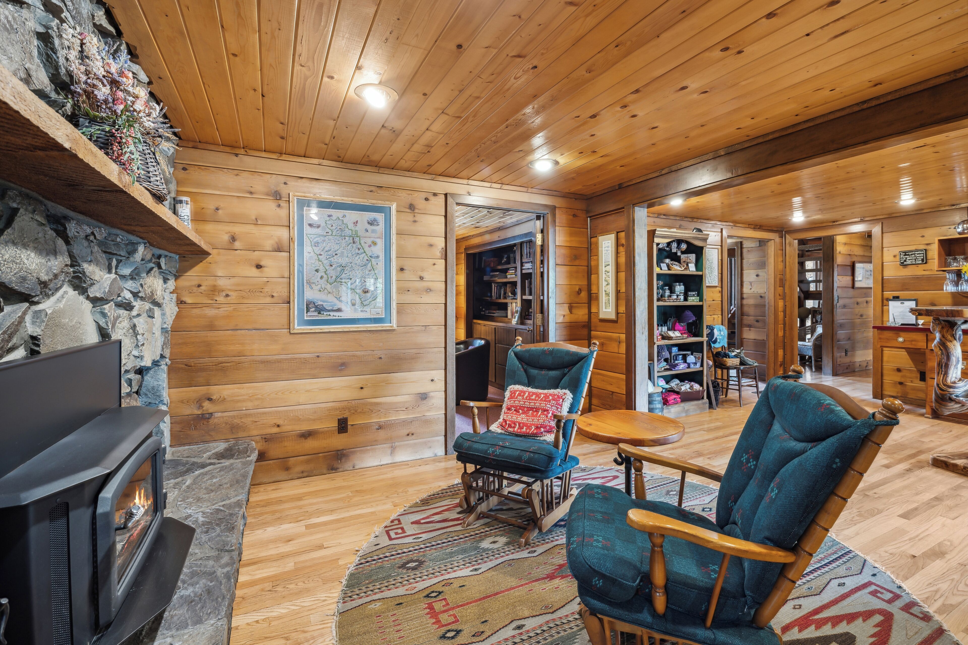 L’intérieur chaleureux d’un chalet avec une cheminée en pierre, des murs en bois et un coin salon confortable.