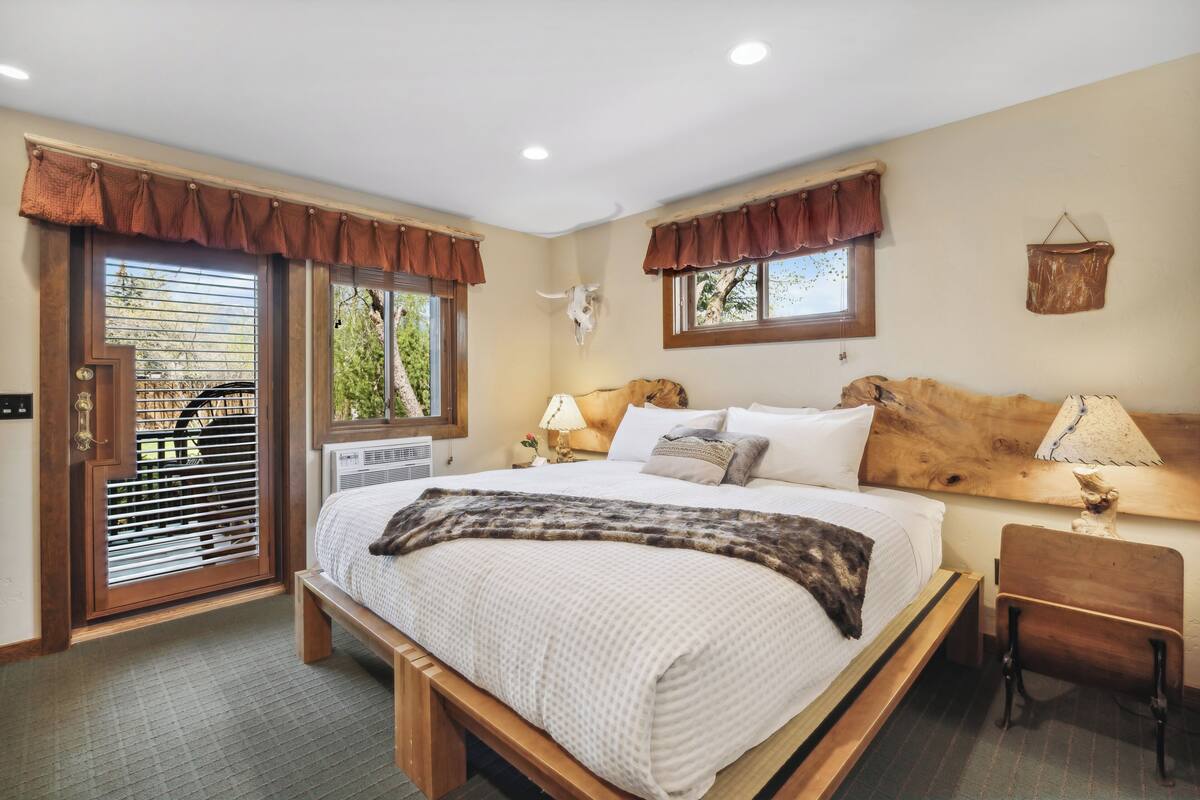 Un dormitorio con una cama grande, cabecera de madera y una ventana con persianas.