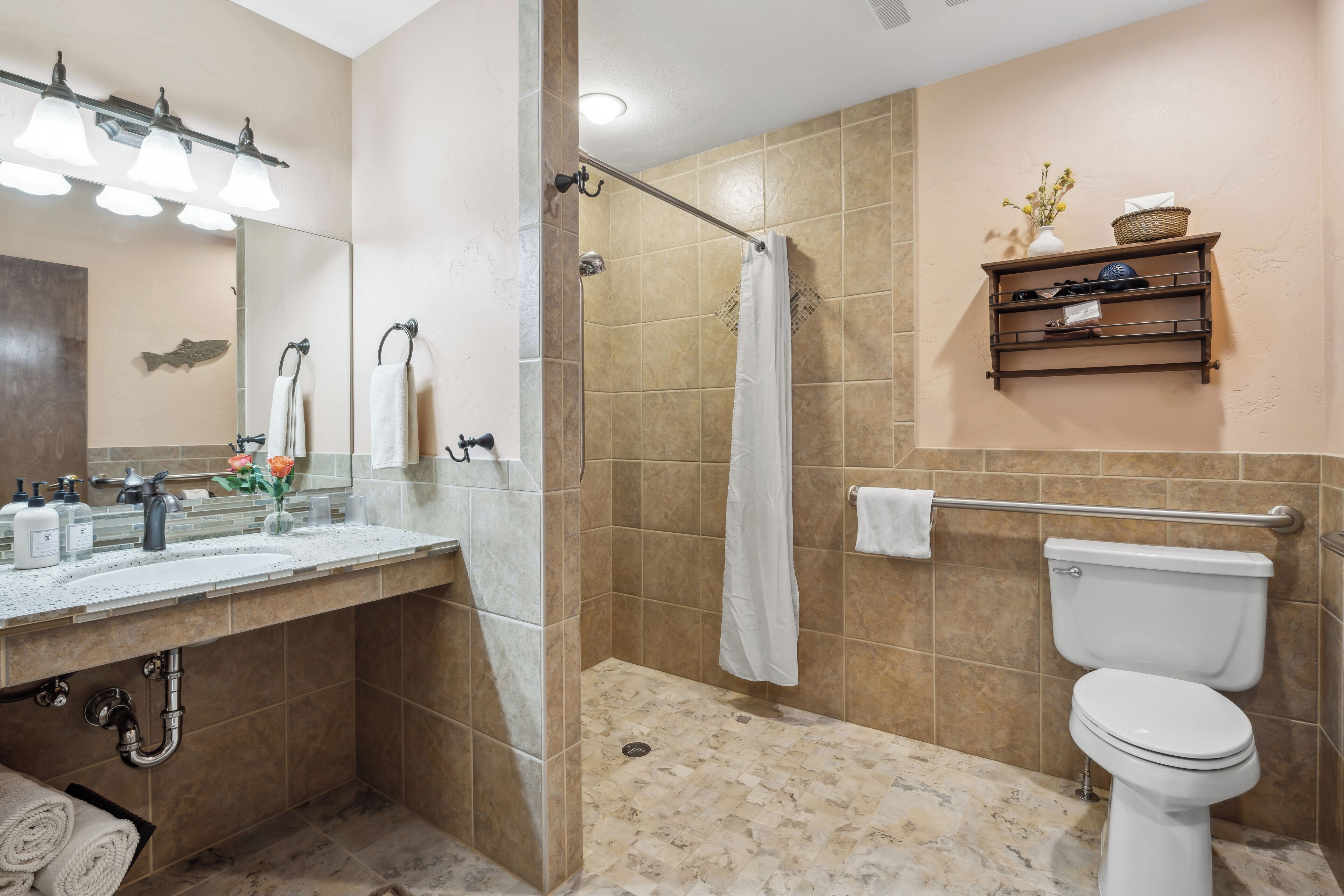Un baño con ducha, inodoro, lavabo y un estante con artículos de aseo.