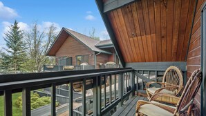 Eine Holzterrasse mit Korbstühlen und Blick auf eine Holzhütte.