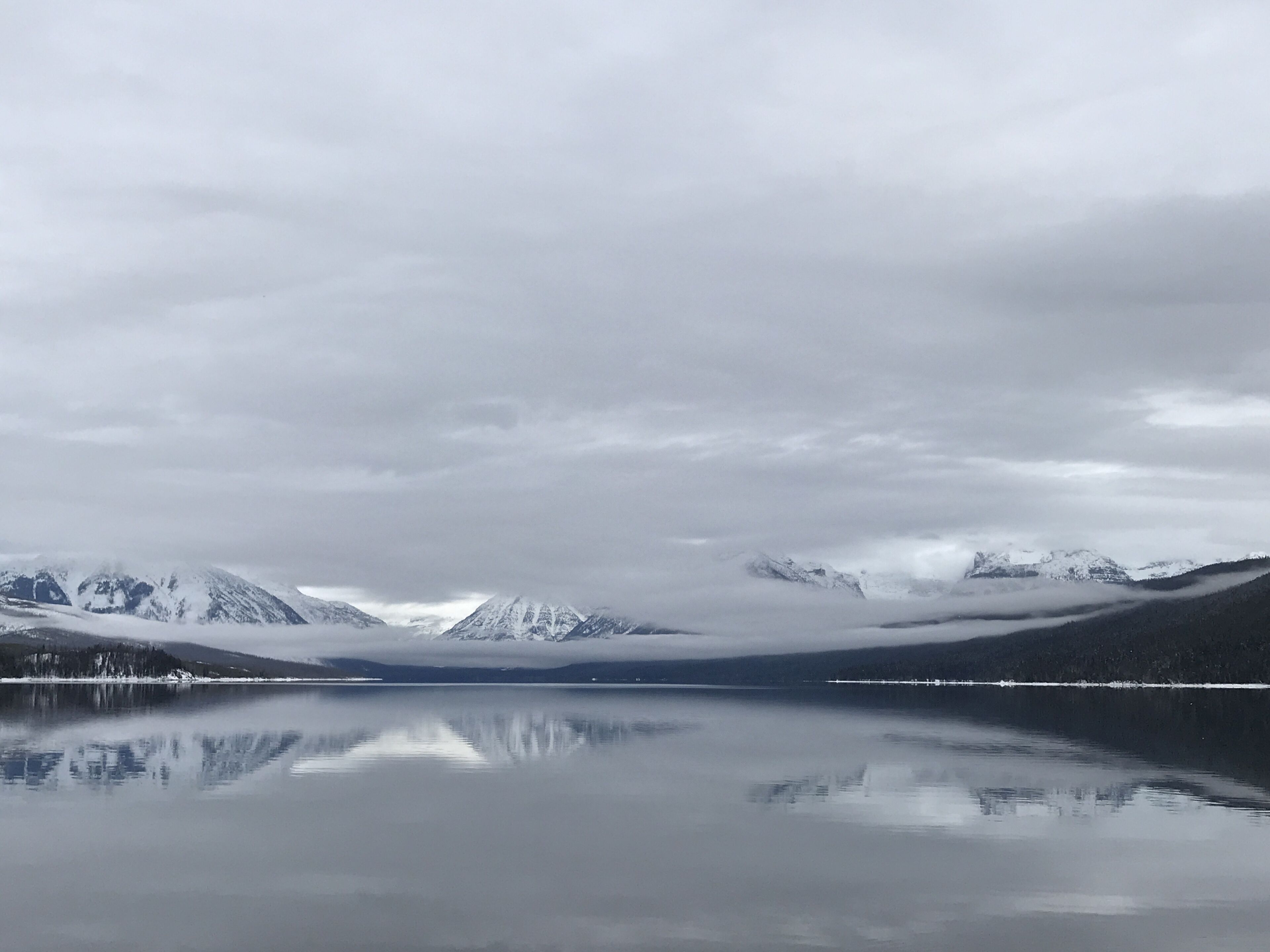 A calm lake with mountains in the background and a clear sky.