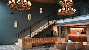 Eine moderne Lobby mit einer großen Eckcouch, einer Treppe und einem Empfangstresen.