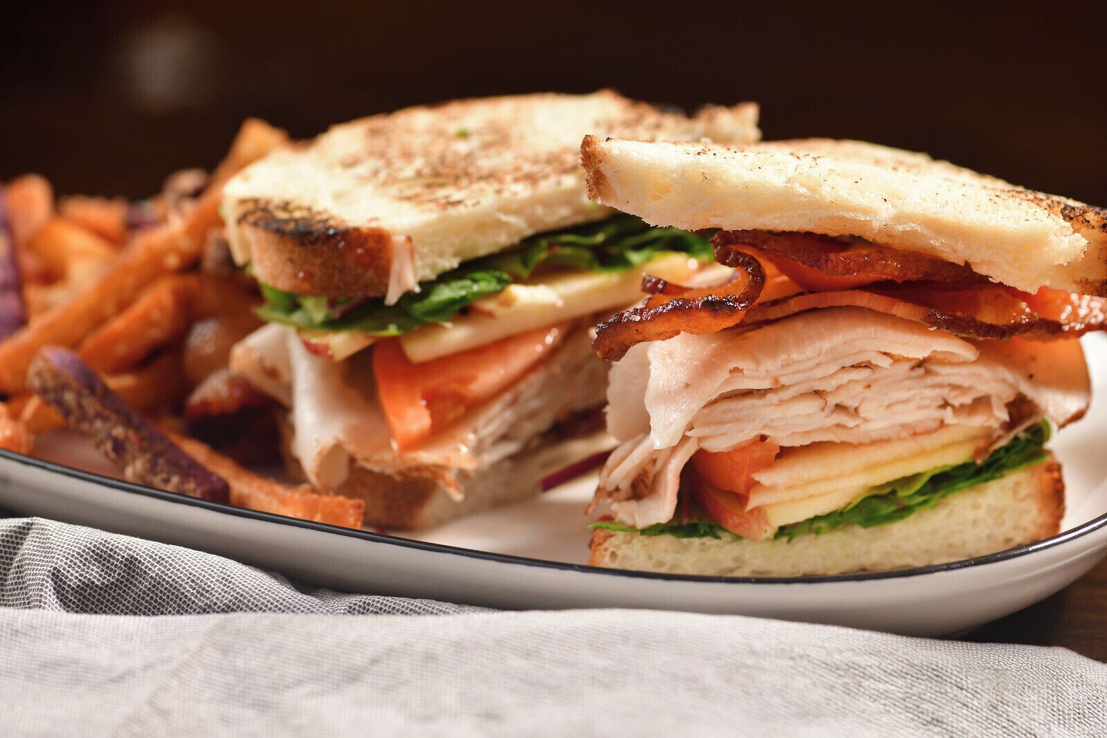 A sandwich with layers of meat, cheese, and lettuce, served on a plate.