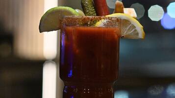 Un cocktail Bloody Mary, agrémenté de diverses garnitures, servi dans un grand verre.