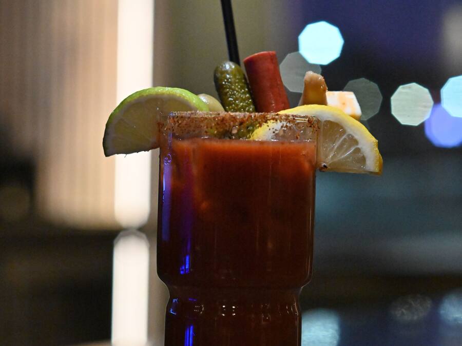 Un cocktail Bloody Mary, agrémenté de diverses garnitures, servi dans un grand verre.