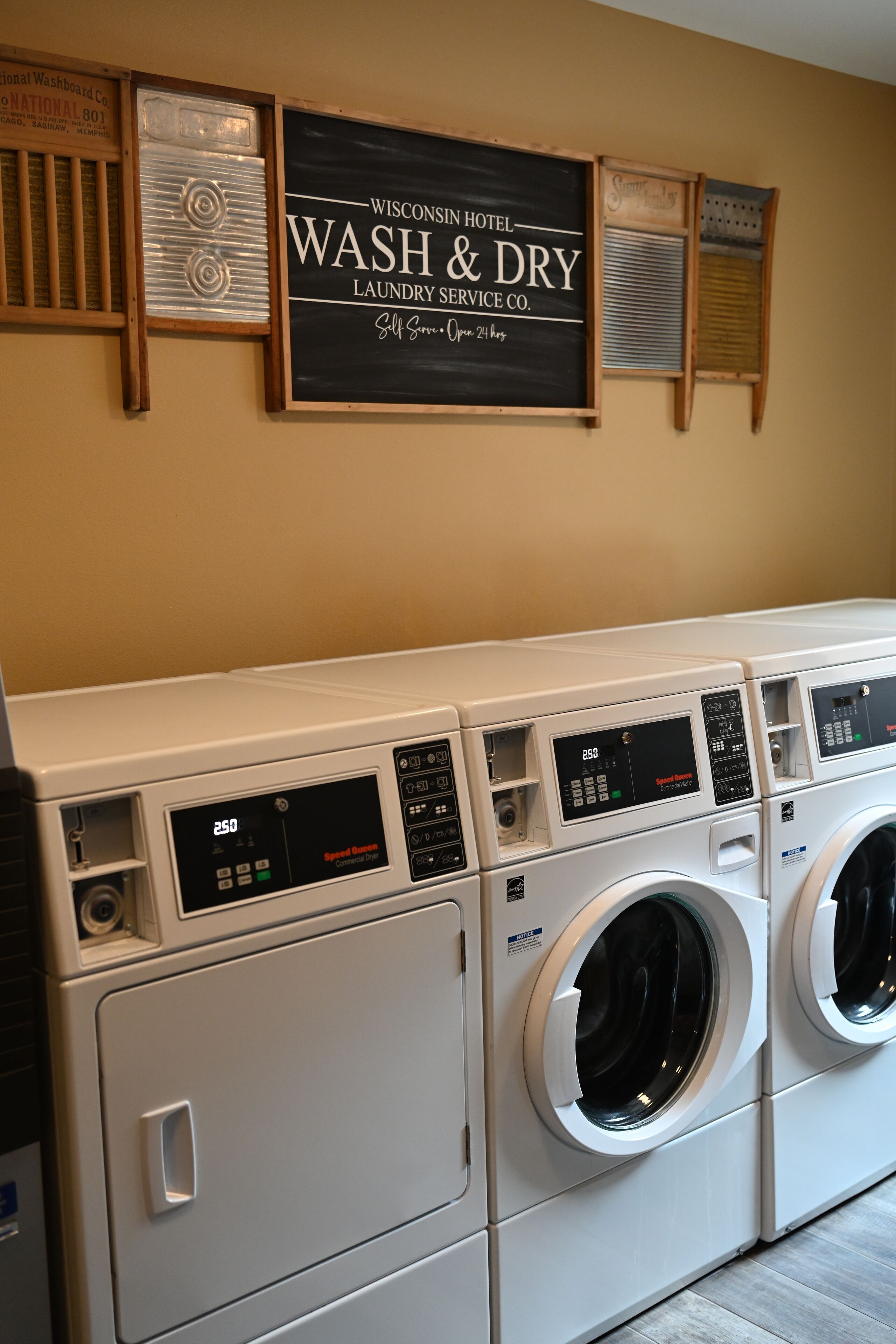 A laundry area with multiple washing machines and a sign above stating "WISCONSIN HOTEL WASH & DRY LAUNDRY SERVICE CO."