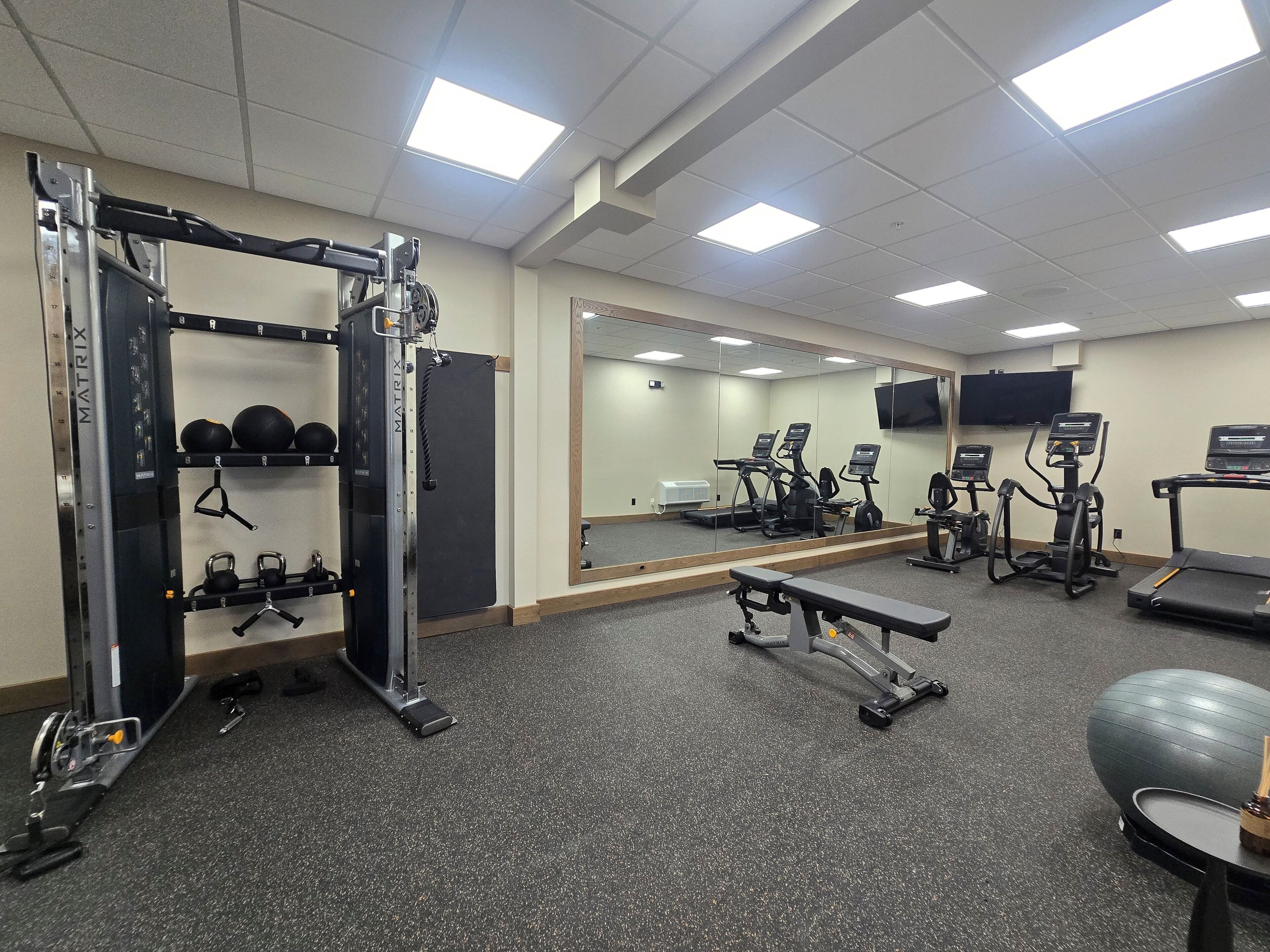 A gym with exercise equipment, a mirrored wall, and a television.