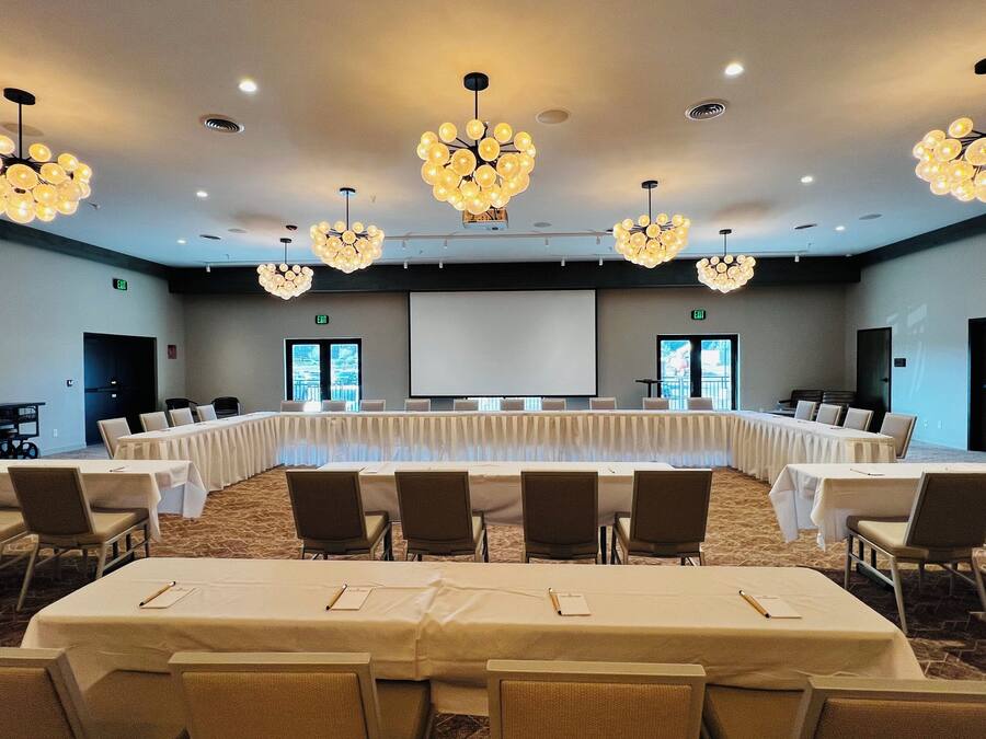 A conference room with a long table, multiple chairs, and chandeliers.