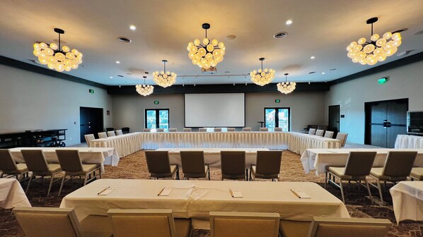 A conference room with a long table, multiple chairs, and chandeliers.