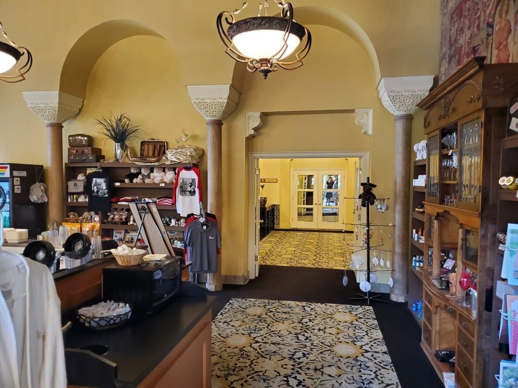 A lobby with a patterned carpet, a reception desk, a display of items, and a hallway leading to another room.