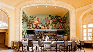 A bar area with a mural, bar counter, and seating.