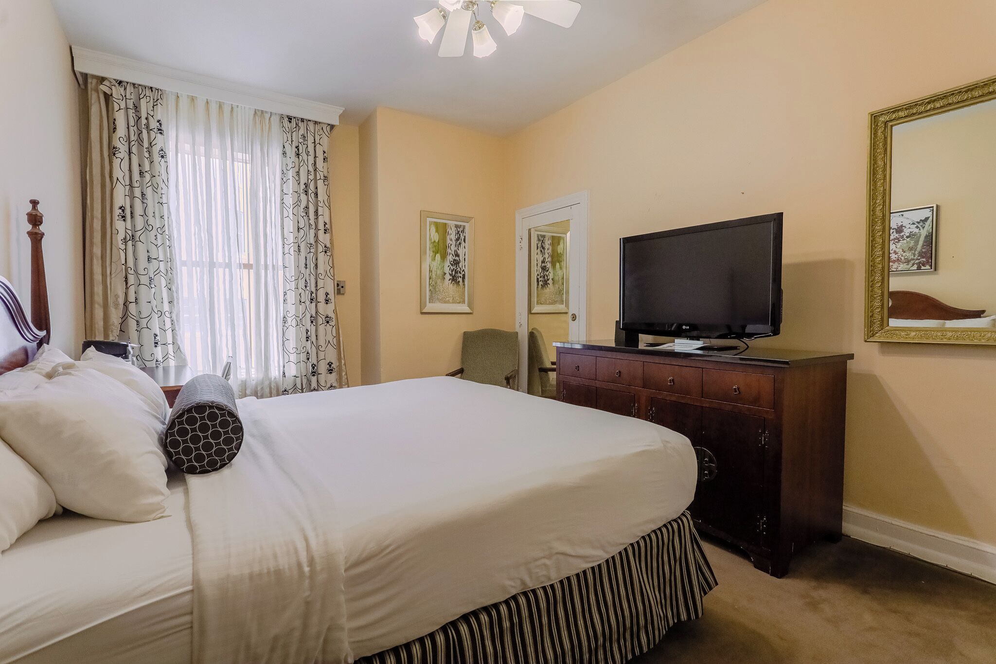 A hotel room with a bed, a television, a dresser, and two framed pictures on the wall.