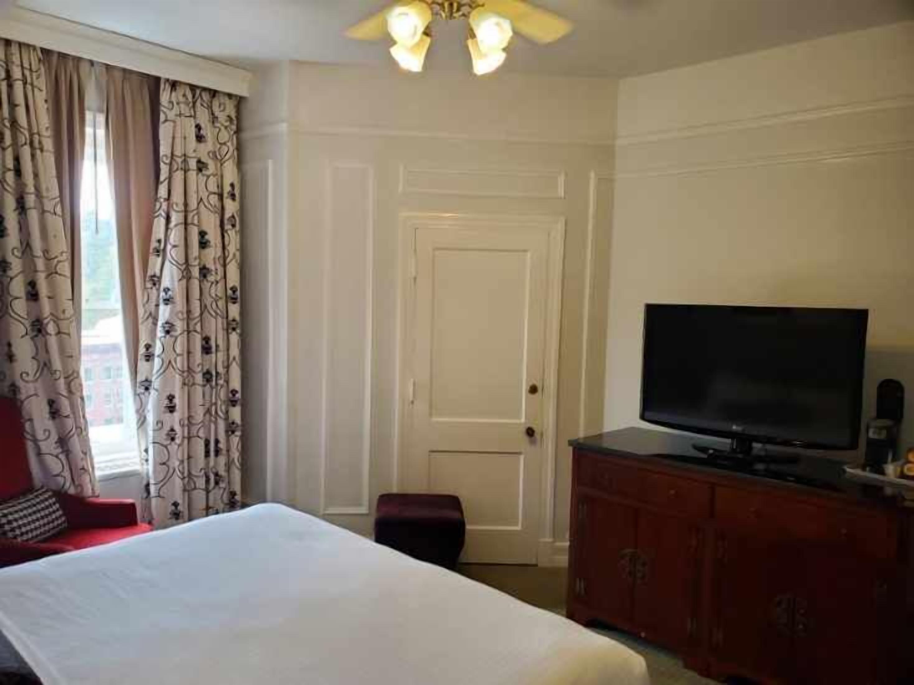 Ein Hotelzimmer mit einem Bett, einem Fernseher, einem Kleiderschrank und einer Tür.
