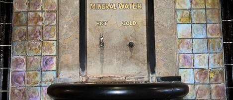 A wall-mounted water fountain labeled "The Hot Springs Mineral Water" with "HOT" and "COLD" taps.