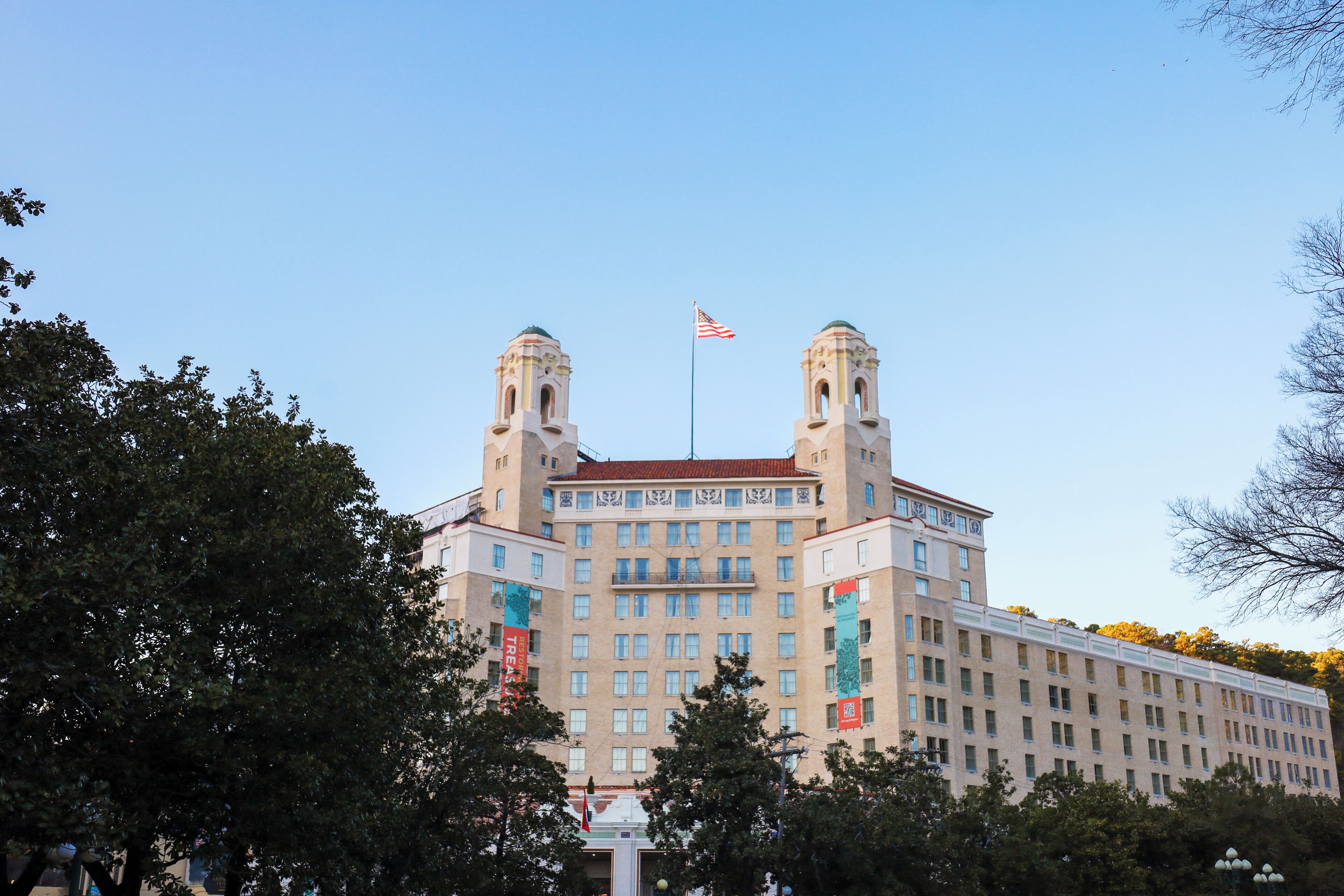 A large, historic building with two towers, a flag, and a central entrance.