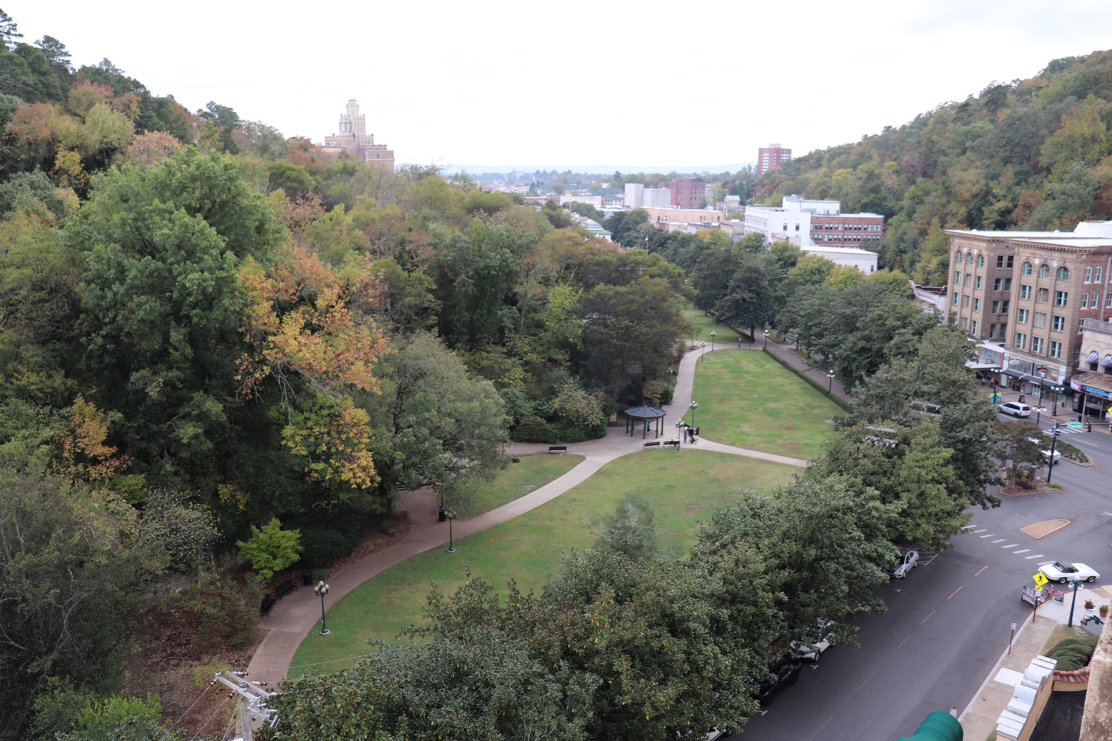 A park with a gazebo, pathways, and a road with vehicles.