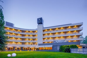 A multi-story hotel with a central tower, multiple balconies, and outdoor seating areas.