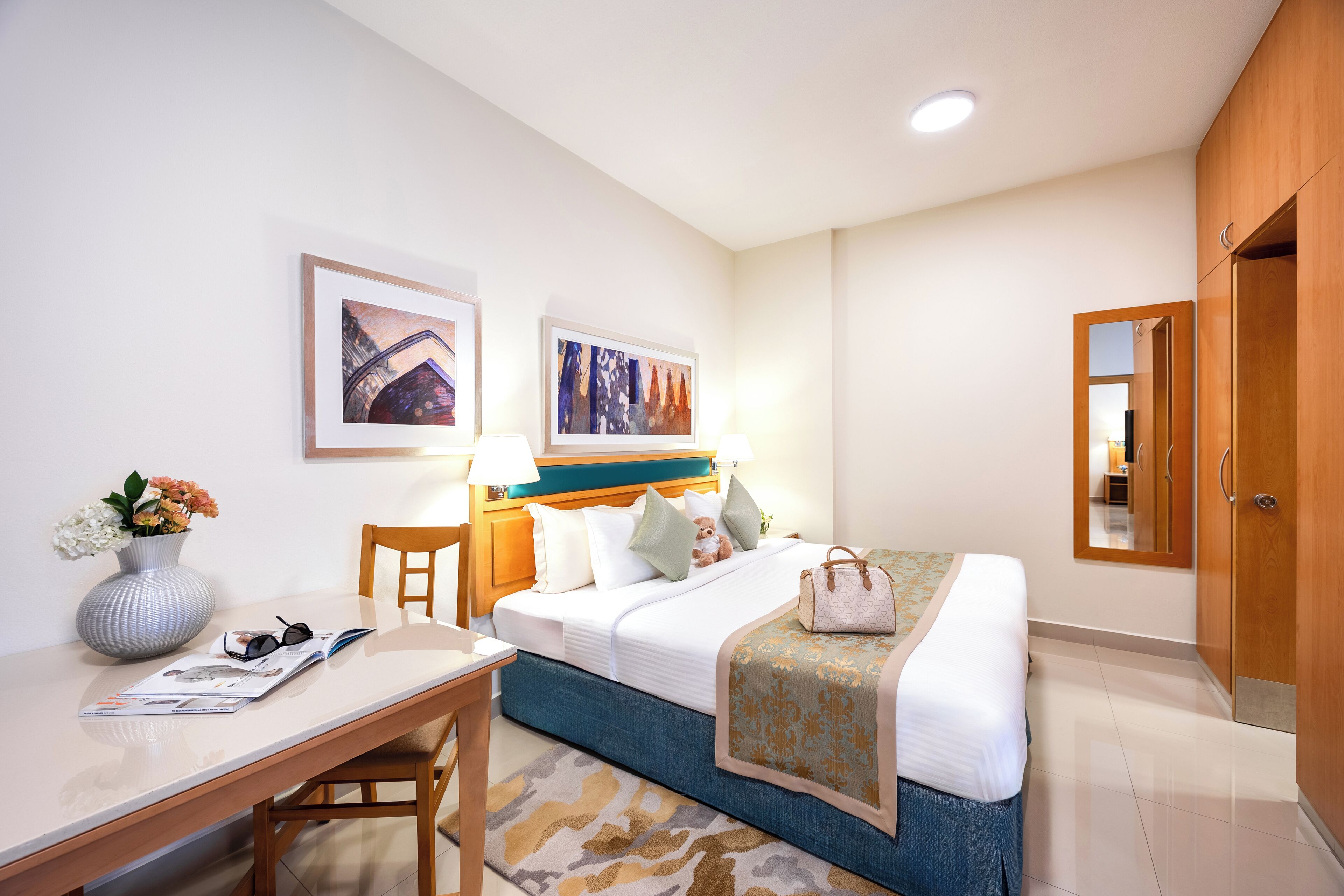A hotel room with a bed, bedside table, lamp, and a mirror.