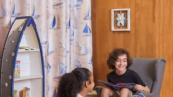 Children can read and relax in this inviting room with a bookshelf and a nautical-themed curtain.