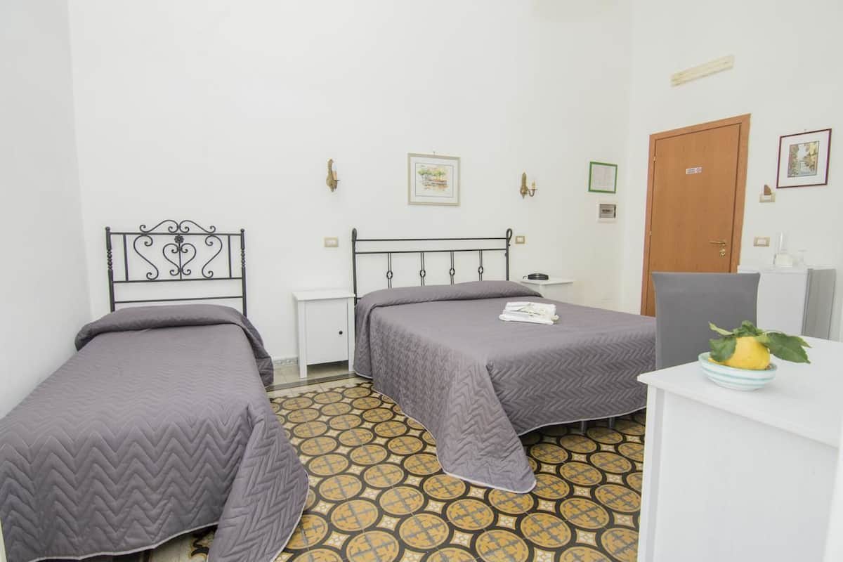 Ein Zimmer mit zwei Einzelbetten, einem Schreibtisch, einem Stuhl und einer Tür.