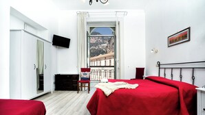 Un dormitorio con una cama grande, un escritorio, una silla y un televisor en la pared.