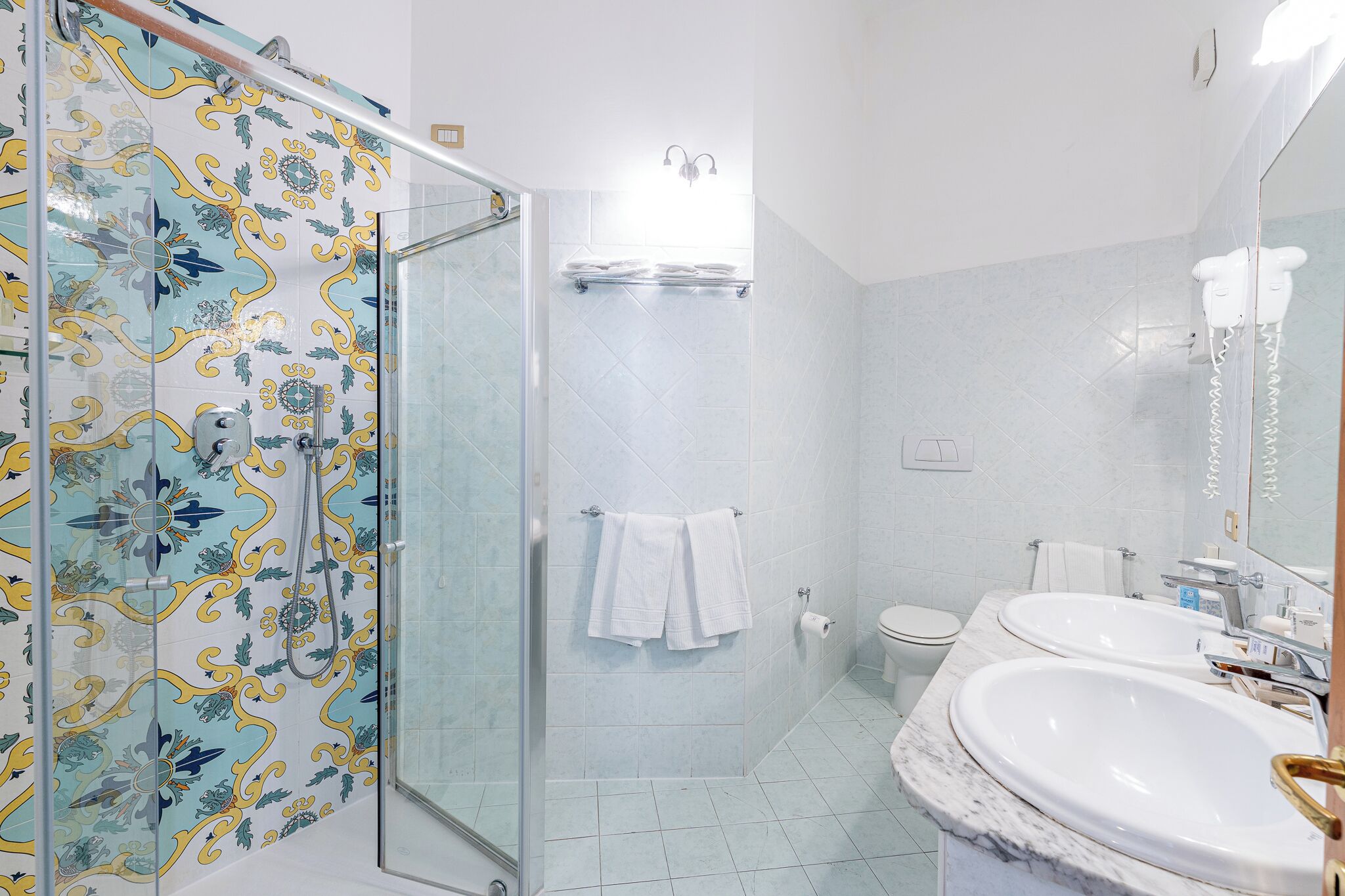 Une salle de bain avec une douche, des toilettes et deux lavabos.